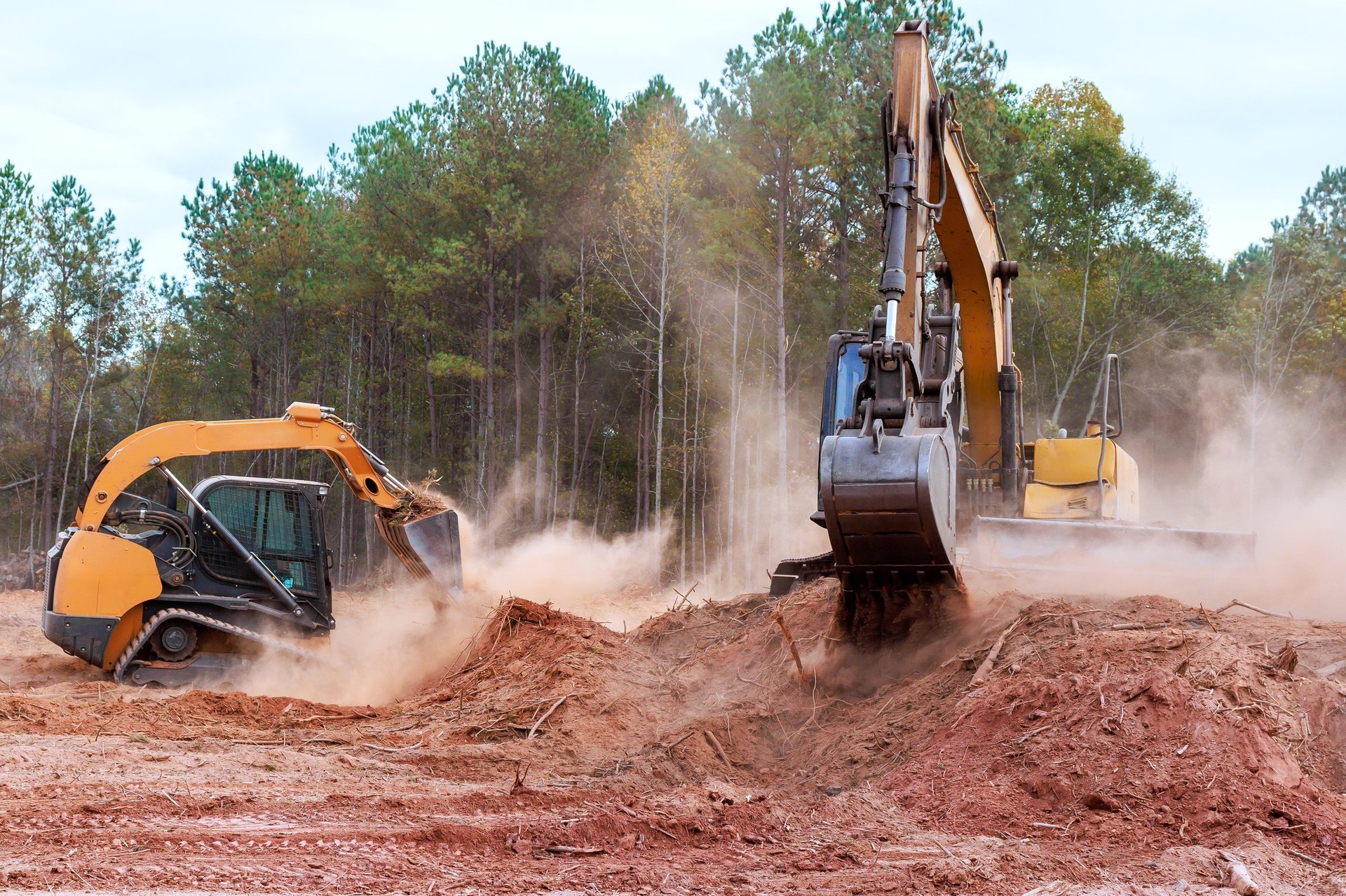 Heavy excavator clearing dirt in wooded location